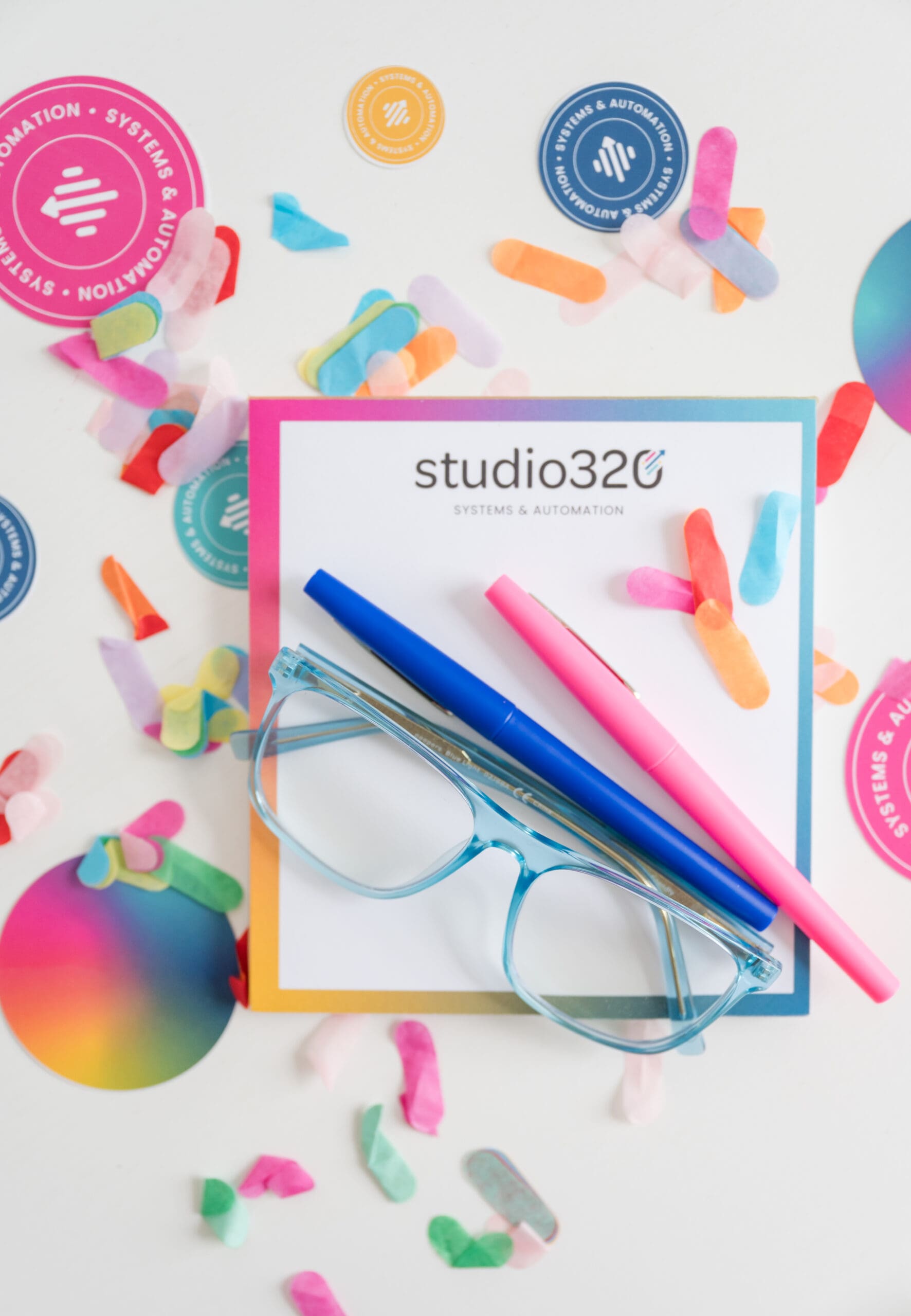 Studio320 branding flat lay with systems and automation stationery, colorful pens, and confetti.