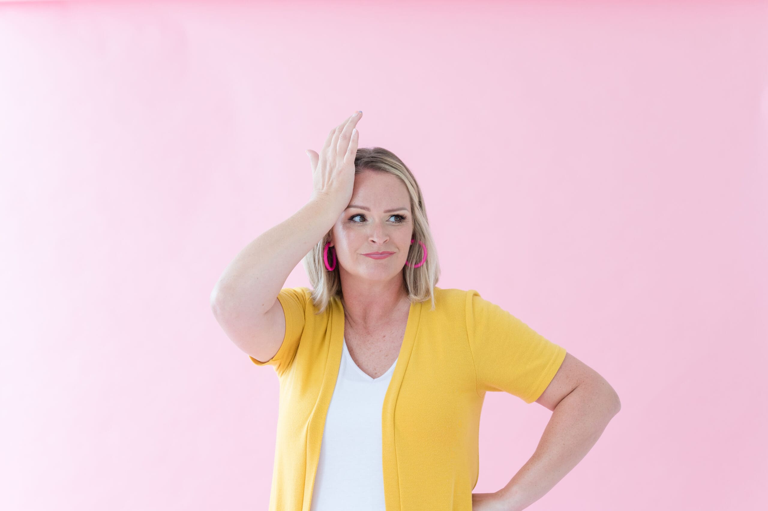 Studio320 founder with confused look on her face and hand to head. Wearing a yellow cardigan.